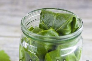 поставете краставици, завинтени в гроздови листа на дъното на буркана